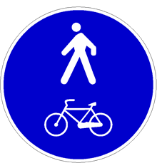 Il segnale raffigurato è posto in corrispondenza di una pista ciclabile a fianco del marciapiede